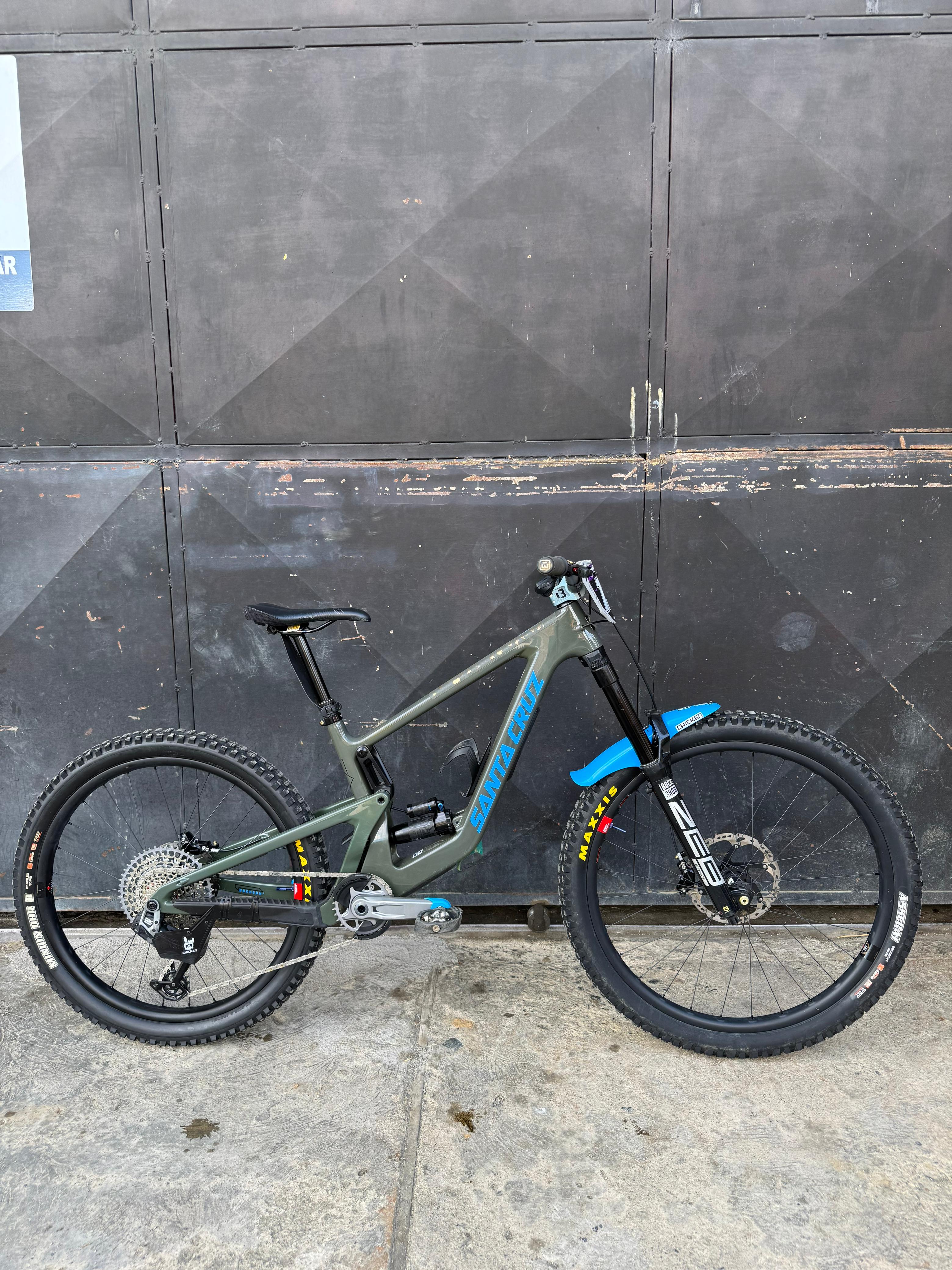 Bicicleta demo Santa Cruz Bronson verde oliva vista de lado en formato vertical.