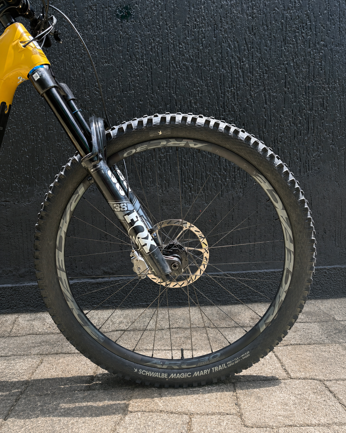 Detalle de la rueda delantera, horquilla y freno de la bicicleta demo Santa Cruz Heckler SL amarilla.