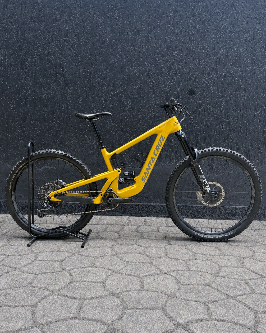 Bicicleta demo Santa Cruz Heckler SL amarilla vista de lado sobre soporte.