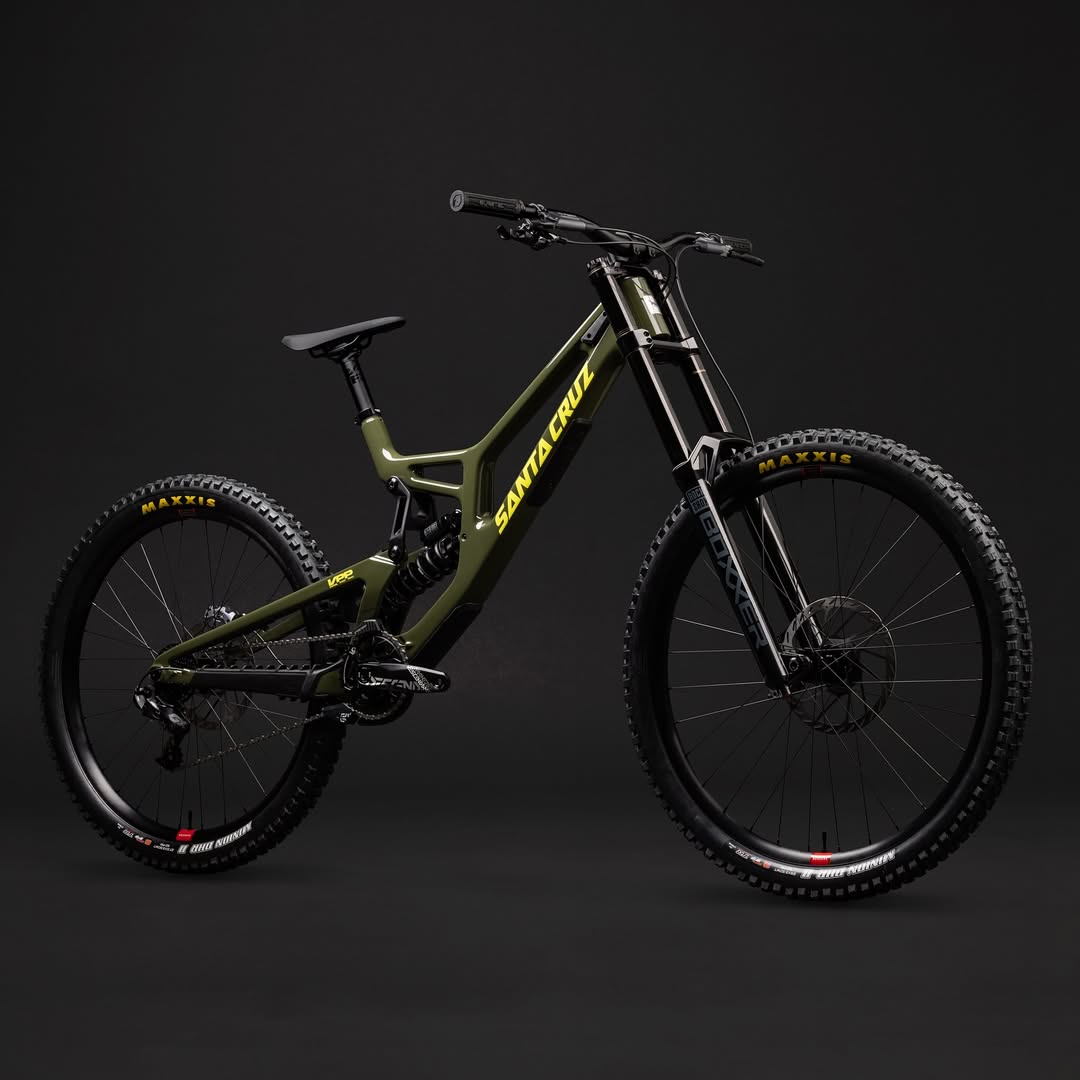 Bicicleta Santa Cruz V10 verde oliva en perspectiva frontal de tres cuartos sobre fondo oscuro.