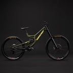 Bicicleta Santa Cruz V10 verde oliva vista de lado sobre fondo oscuro de estudio.