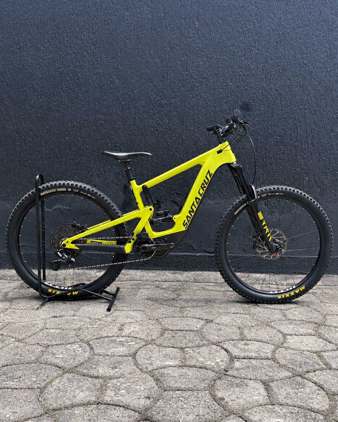 Bicicleta usada Santa Cruz Heckler 8 verde lima en vista lateral sobre soporte de exhibición.