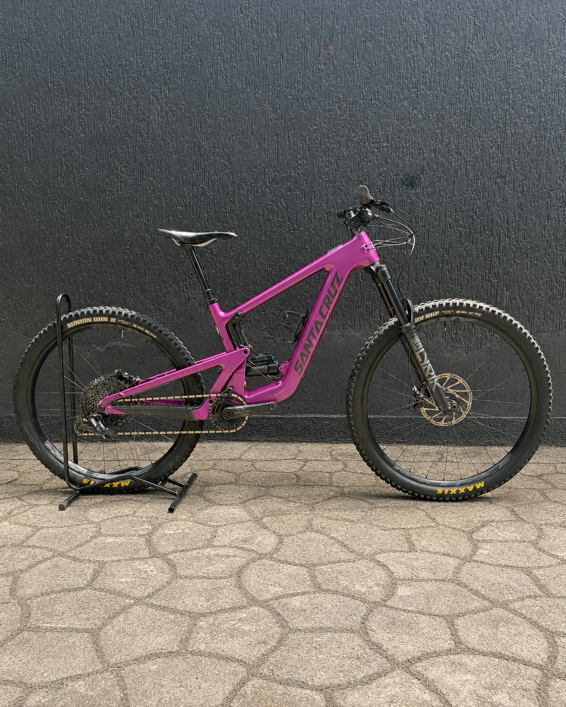 Bicicleta usada Santa Cruz Heckler SL rosa en vista lateral sobre soporte de exhibición.