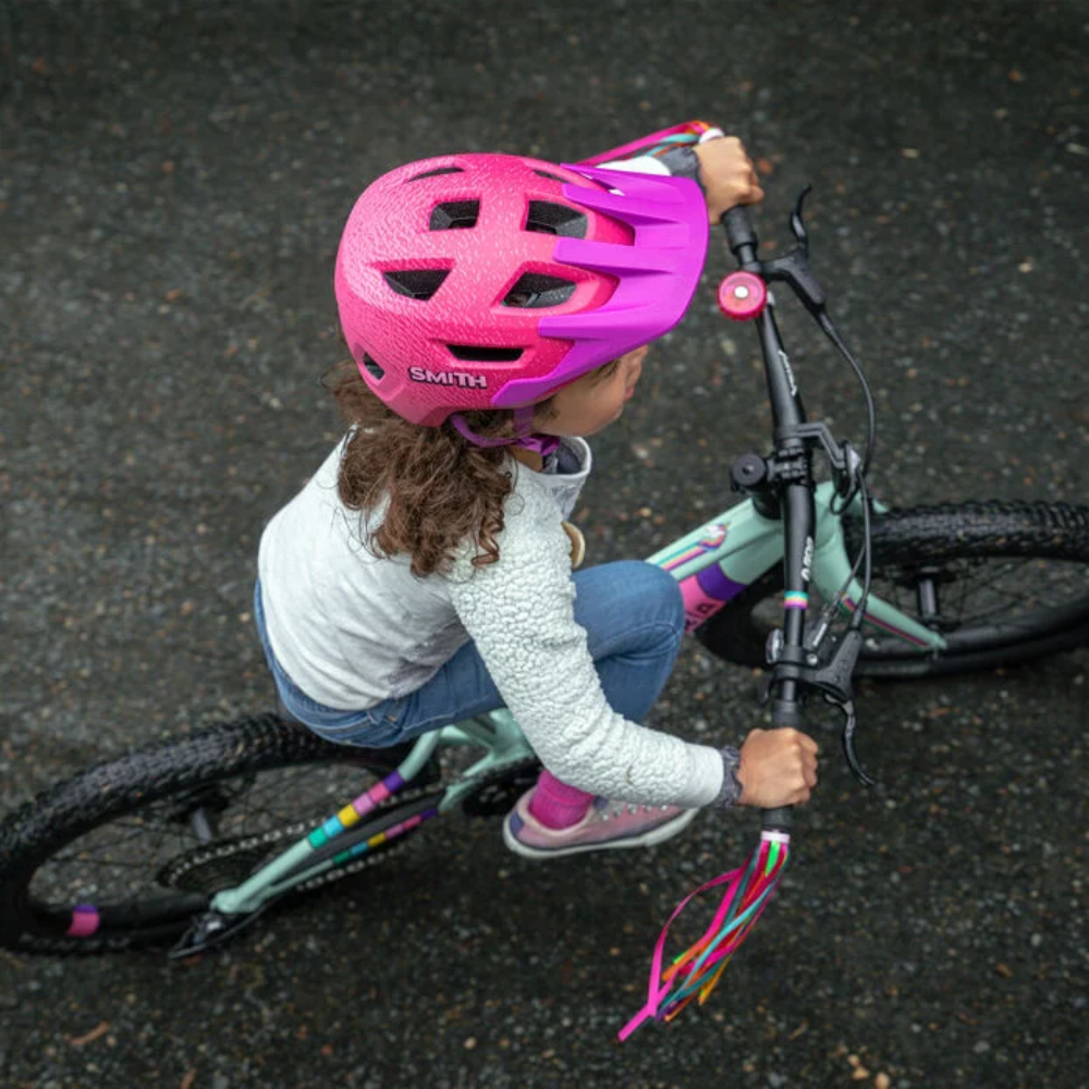 Niña usando casco Smith Sidekick Jr Matte Lollipop Fade mientras monta bicicleta, vista superior