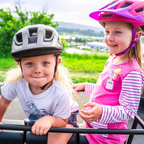 Dos niños usando cascos Smith Sidekick Jr Matte Black y Matte Lollipop Fade, retrato frontal al aire libre
