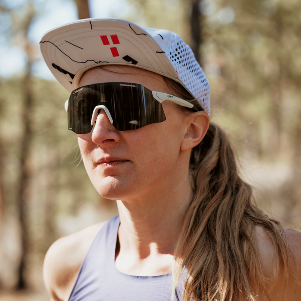 Corredora usando gafas Smith Vert Running Matte Bone con lente negra espejo ChromaPop, vista lateral al aire libre