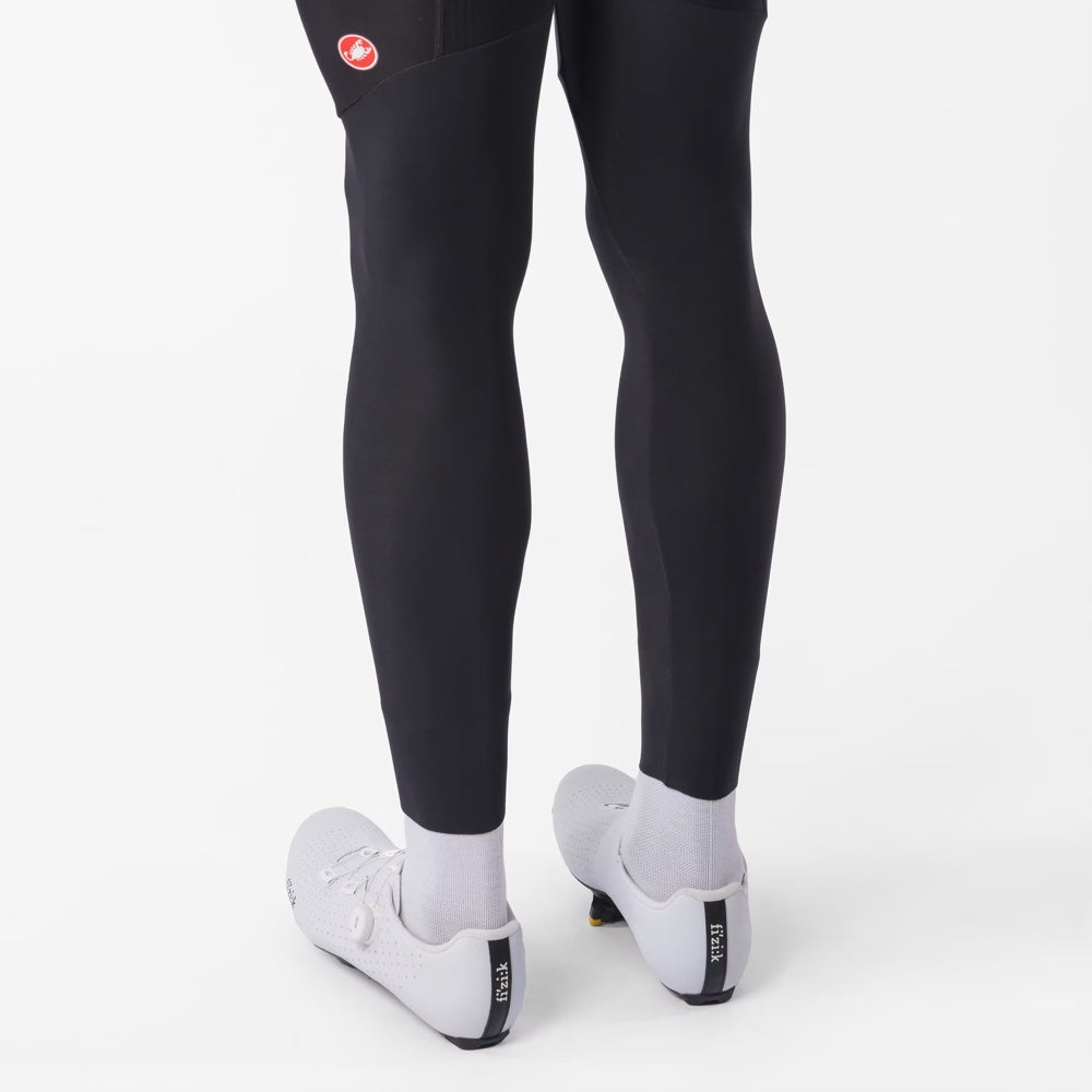 Pantalón Castelli Competizione Bibtight negro, detalle posterior de los tobillos con zapatillas blancas.